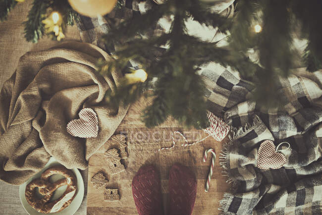 Mulher em pé junto a uma árvore de Natal ao lado de decorações, biscoitos e pretzel — Fotografia de Stock