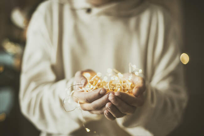 Garçon tenant des lumières de corde de Noël dans sa main — Photo de stock