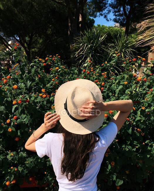 Вид сзади на женщину, стоящую в саду с рукой на голове, побережье Амальфи, Кампания, Италия — стоковое фото