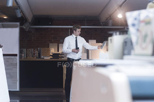 Man standing in a shop looking at a floor tile, Germany — Stock Photo