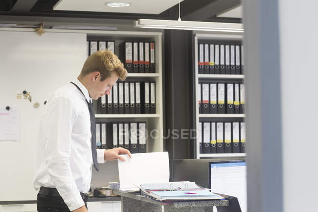 Salesman standing in a shop's office looking at a brochure, Germany — Stock Photo