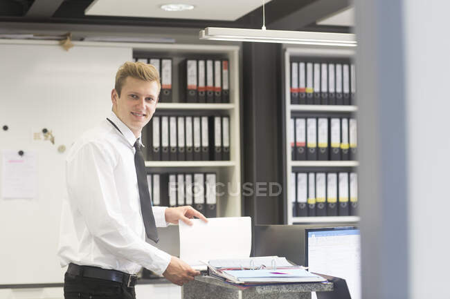 Smiling Salesman standing in a shop's office looking at a brochure, Germany — Stock Photo