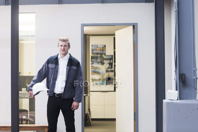 Portrait of a technician standing in an office holding a hard hat, Germany — Stock Photo