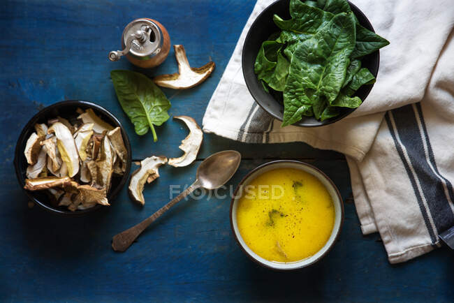 Cuenco de champiñones y sopa de espinacas junto a ingredientes crudos - foto de stock
