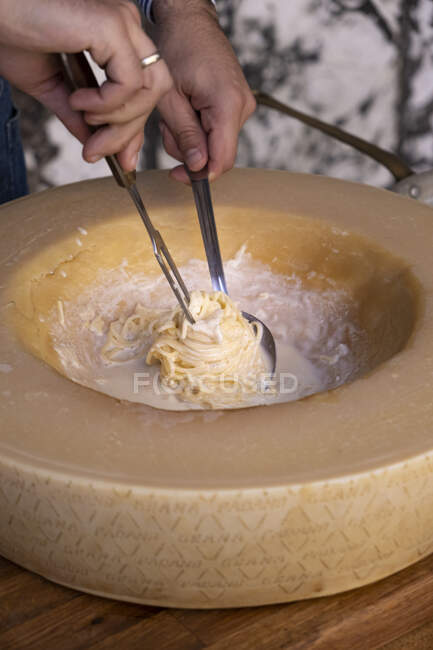 Mann bereitet Pasta in einem Padano Grana Käserad zu — Stockfoto