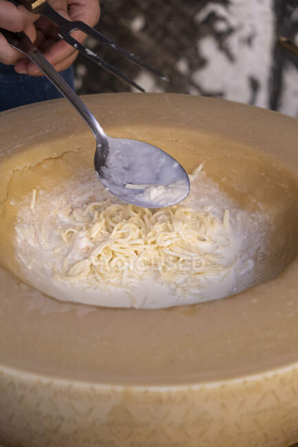 Mann bereitet Pasta in einem Padano Grana Käserad zu — Stockfoto
