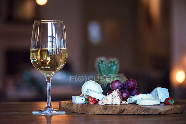 Glass of white wine next to a cheese board — Stock Photo