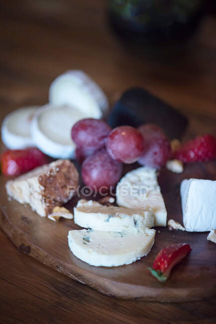 Primer plano del queso y las uvas en una tabla de quesos - foto de stock