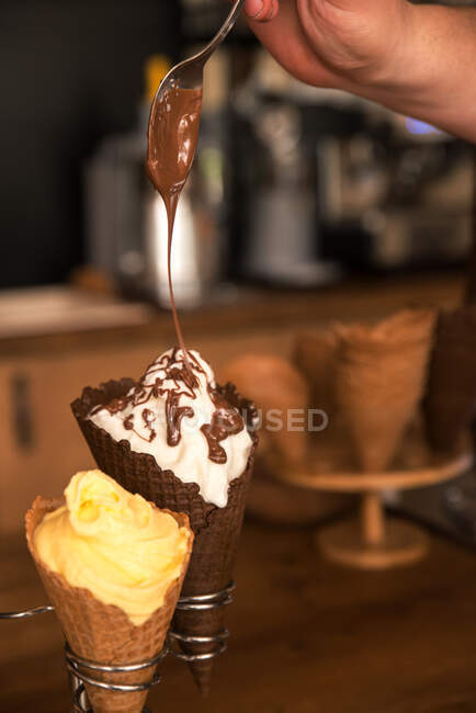 Homem pingando chocolate derretido em um sorvete — Fotografia de Stock