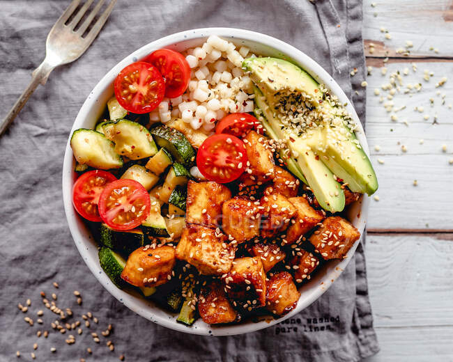 Pan fried tofu with pearl cous-cous, fried courgette, avocado, tomato and sesame seeds — Stock Photo