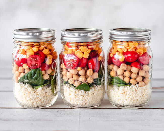 Three meal jars with millet, spinach, chickpea, tomato and corn — Stock Photo