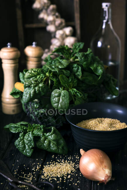 Шпинат, лук, чеснок и болгарская пшеница на деревянном столе — стоковое фото