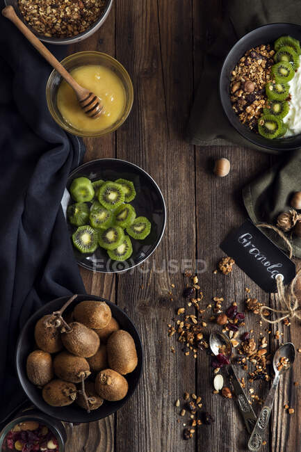 Overhead view of breakfast granola with honey, nuts, yogurt and kiwi fruit — Stock Photo