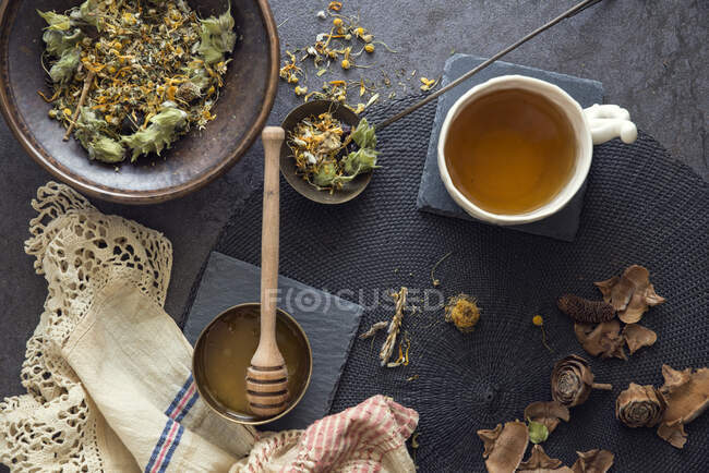 Taza de té de hierbas con miel junto a los ingredientes - foto de stock