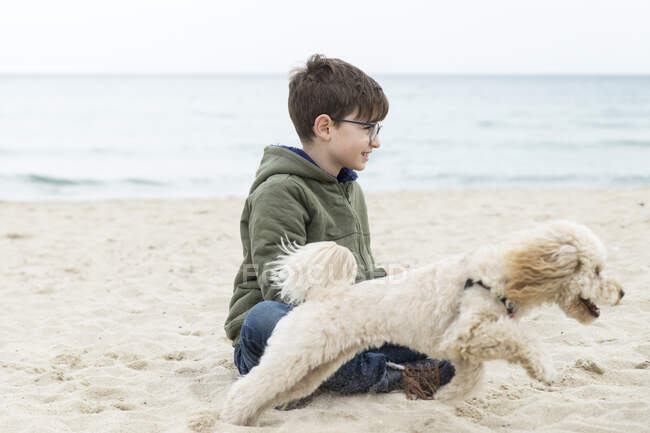 Menino brincando com seu cão na praia, Bulgária — Fotografia de Stock