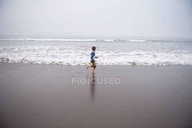 Хлопчик біжить уздовж пляжу (Каліфорнія, США). — стокове фото