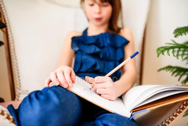 Девушка сидит на стуле и делает домашнее задание — стоковое фото