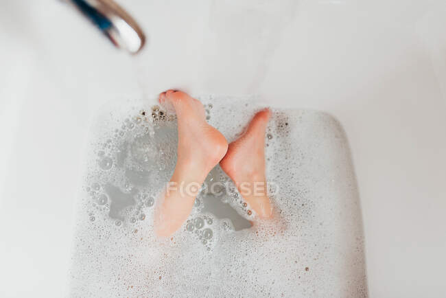 Крупный план ног мальчика в ванне с пеной — стоковое фото