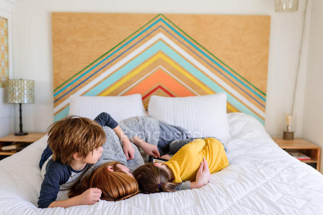 Мать и дети обнимаются на кровати — стоковое фото