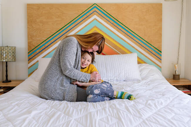 Mãe e filha abraçando na cama em casa — Fotografia de Stock