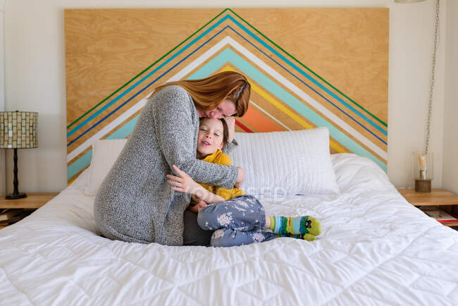 Мать и маленькая дочь обнимаются на кровати — стоковое фото