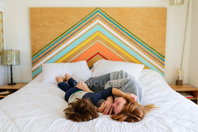 Mãe e filho deitado e abraçando juntos na cama — Fotografia de Stock