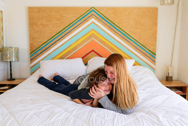 Mãe e filho deitado e abraçando juntos na cama — Fotografia de Stock