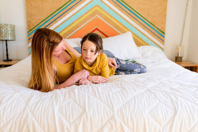 Madre e hija acostadas juntas en la cama - foto de stock