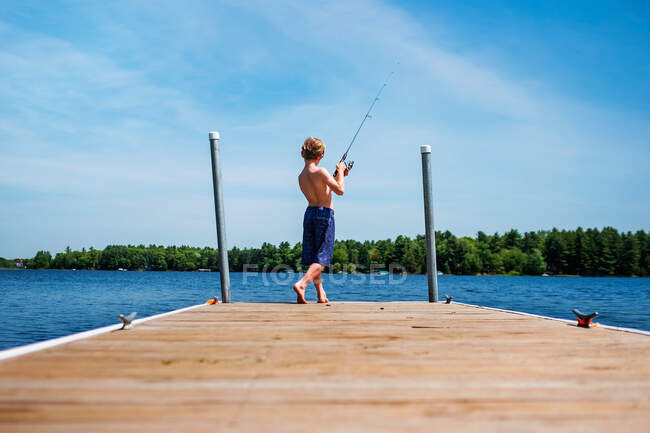 Boy standing on a pier fishing, USA — Stock Photo