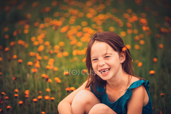 Ragazza felice seduta in un prato con fiori di campo, USA — Foto stock