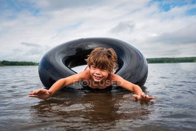 Joyeux garçon flottant dans un anneau gonflable en caoutchouc dans un lac, États-Unis — Photo de stock