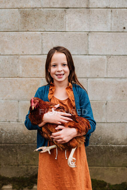 Portrait of a smiling girl holding a chicken, USA — Stock Photo