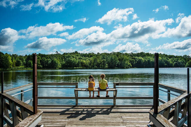 Vue arrière de deux enfants assis sur une jetée, États-Unis — Photo de stock