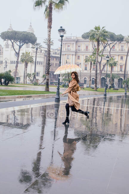 Mujer corriendo por la ciudad bajo la lluvia, Roma, Lazio, Italia - foto de stock