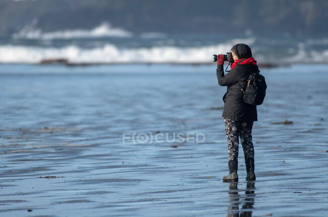 Mulher de pé na praia tirando uma foto, Pacific Rim National Park, Vancouver Island, Vancouver, British Columbia, Canadá — Fotografia de Stock