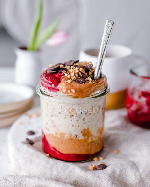 Jar of oatmeal with chocolate chip, chopped nuts, peanut butter and jam — Stock Photo