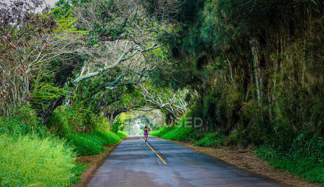 Woman jogging down the middle of a road, Maui, Hawaii, USA — Stock Photo