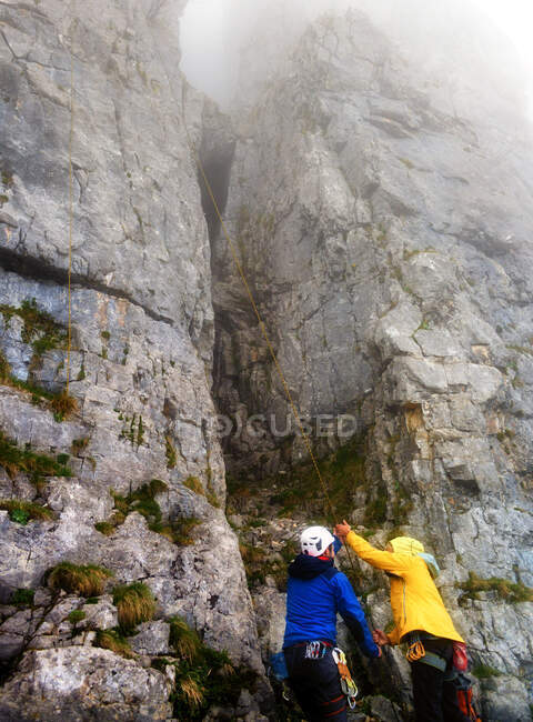 Man and woman mountain climbing in the fog, Ebenalp, Switzerland — Stock Photo