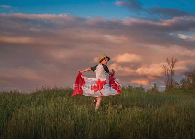 Ragazzo che corre in un campo con una bandiera canadese, Bedford, Halifax, Nuova Scozia, Canada — Foto stock