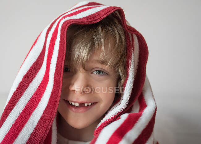 Портрет улыбающегося мальчика с красно-белым полотенцем на голове — стоковое фото