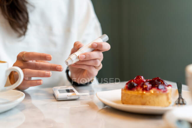 Donna che controlla i suoi livelli di insulina prima di mangiare una torta — Foto stock
