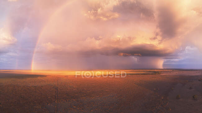 Tramonto tempestoso con doppio arcobaleno, nuvole di cumulo torreggianti e cellule piovose su un lago asciutto in Australia — Foto stock