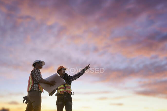 Два будівельники на будівельному майданчику дивляться на плани, Таїланд. — стокове фото