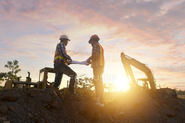 Deux travailleurs de la construction sur un chantier de construction regardant les plans, Thaïlande — Photo de stock