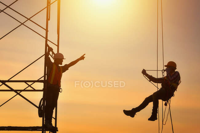 Silueta de dos trabajadores de la construcción en una obra de construcción, Tailandia - foto de stock