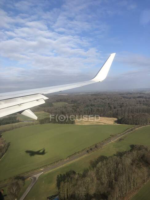 Aircraft wing and shadow of a plane  flying over rural landscape near Billund, Jutland, Denmark — Stock Photo