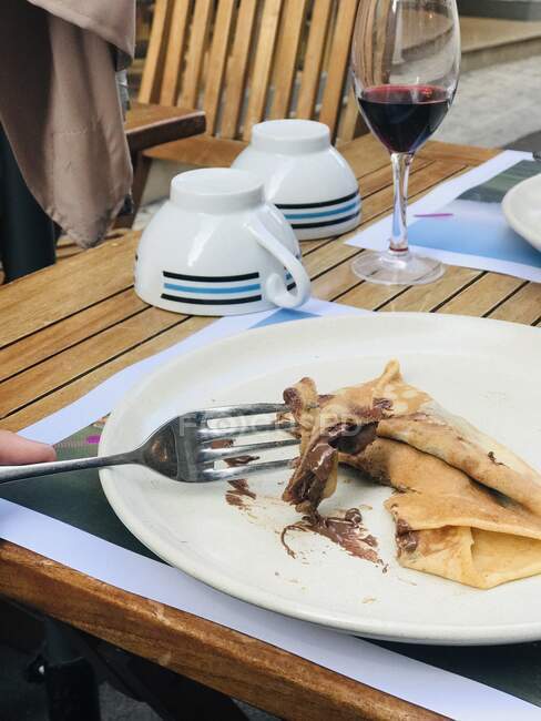 Person eating a chocolate pancake with red wine, France — Stock Photo