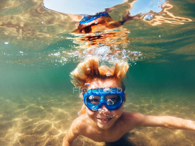 Sonriente niño nadando bajo el agua en un lago, EE.UU. - foto de stock