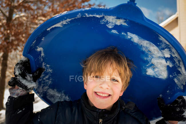 Retrato de um menino sorridente carregando um trenó, EUA — Fotografia de Stock