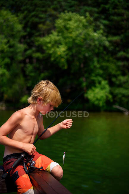 Ein kleiner Junge beim Angeln auf einem Steg im Sommer, USA — Stockfoto